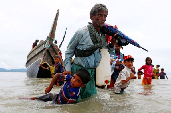 Um refugiado da comunidade rohingya puxa uma criança ao sair na costa bengali após atravessar a fronteira do Bangladesh - Sputnik Brasil