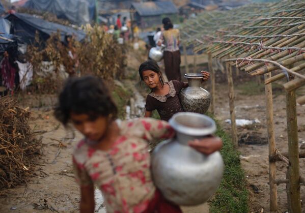 Menina refugiada rohingya carrega um jarro de metal com água em um campo de refugiados bengali - Sputnik Brasil
