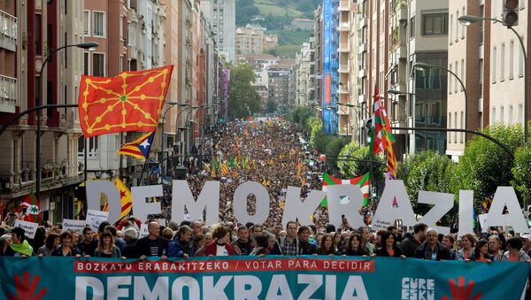 Milhares de manifestantes caminham atrás de uma bandeira em que se lê Votar para decidir Democracia, Catalunha, estamos com você, durante uma marcha organizada pela organização de independência pro-basca. - Sputnik Brasil