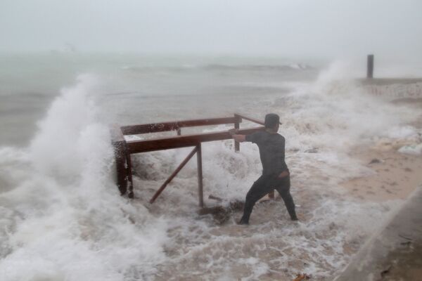 Homem tenta retirar mesa levada ao mar durante o furacão Maria - Sputnik Brasil