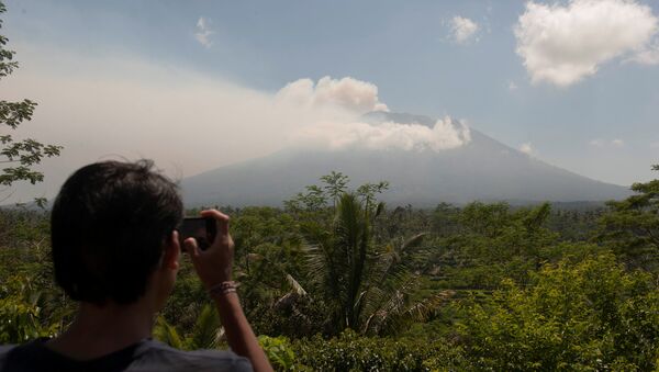 A local resident takes a picture of Mount Agung, an active volcano that authorities say is showing increased activity, from a monitoring station in Rendang Village, Karangasem on the resort island of Bali, Indonesia September 19, 2017 - Sputnik Brasil