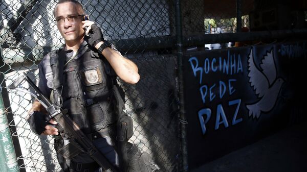 Policial militar ao lado de uma mensagem de paz na comunidade da Rocinha, no Rio de Janeiro - Sputnik Brasil