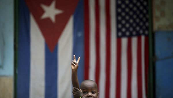 Eric, 3, gestures while posing for a photograph in front of the Cuban and U.S. flags in Havana, March 25, 2016. - Sputnik Brasil