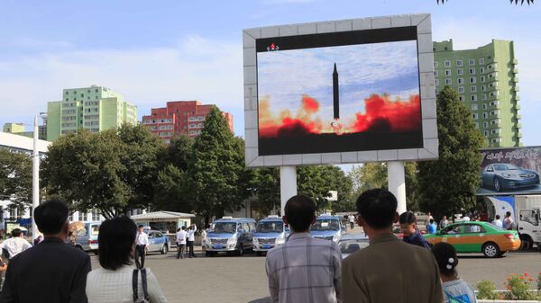 As pessoas a ver o lançamento do míssil balístico Hwasong-12 na televisão da estação ferroviária em Pyongyang, Coreia do Norte, 16 de setembro de 2017 - Sputnik Brasil