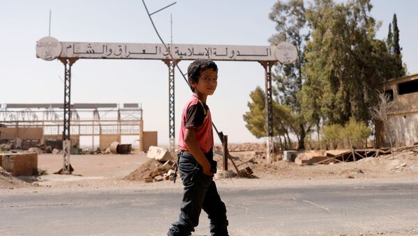 A boy walks past a sign which reads 'Islamic State in Iraq and Syria' as fighting continues between the Syrian Democratic Forces and Islamic State militants in Raqqa, Syria, August 20, 2017 - Sputnik Brasil