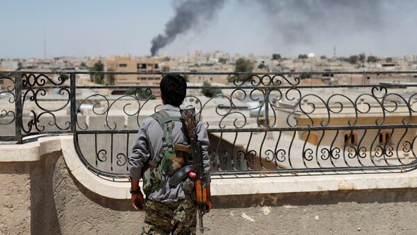 Soldado curdo olhando para fumaça depois de ataques aéreos da coalizão em Raqqa - Sputnik Brasil