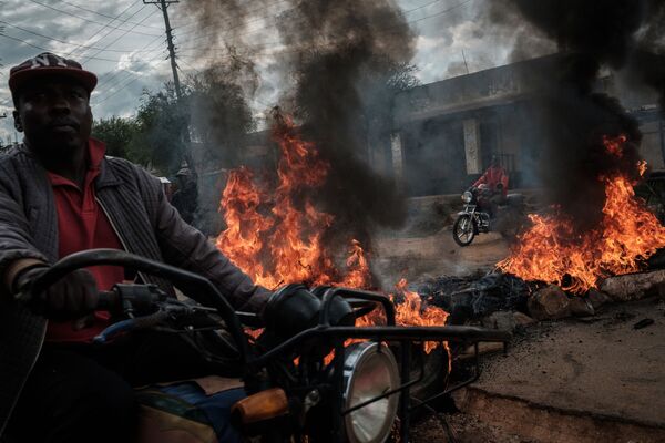 Motociclista passa pelas barricadas em chamas na rua, instaladas pelos apoiantes do candidato do partido NASA (Super Aliança Nacional) nas eleições presidenciais, Raila Odinga, no Quênia - Sputnik Brasil
