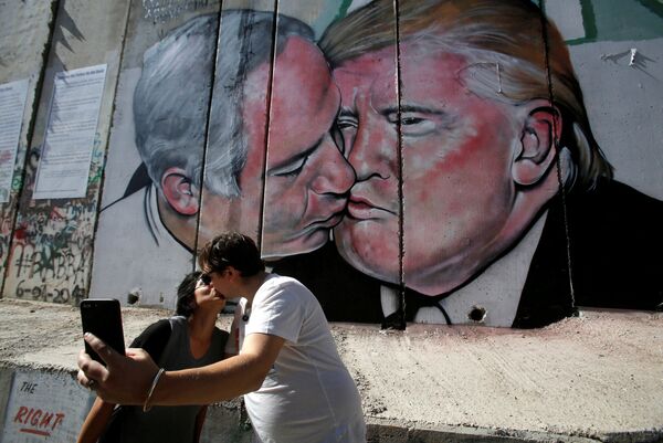 Turistas se beijam perto do grafite retratando um beijo entre o presidente dos EUA, Donald Trump, e o premiê israelense, Benjamin Netanyahu, na Cisjordânia - Sputnik Brasil