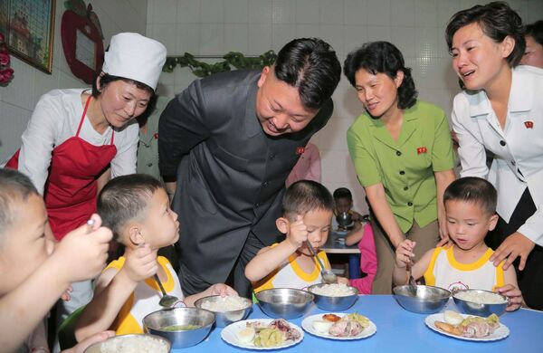 O líder norte-coreano Kim Jong-un sorri para as crianças enquanto estas comem no orfanato de Pyongyang, no Dia Internacional da Criança - Sputnik Brasil