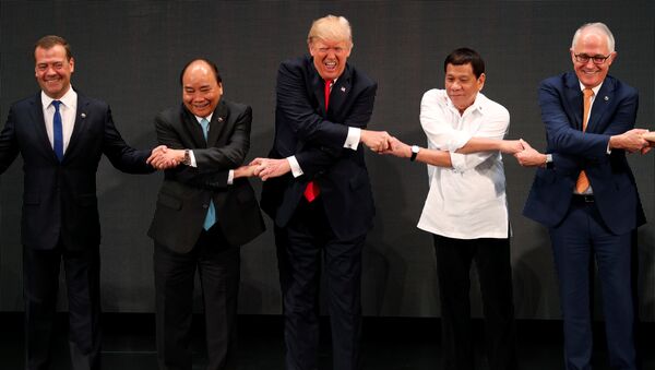 U.S. President Donald Trump smiles with other leaders, including Russia's Prime Minister Dmitry Medvedev, Vietnam's Prime Minister Nguyen Xuan Phuc, President of the Philippines Rodrigo Duterte and Australia's Prime Minister Malcolm Turnbull, as they cross their arms for the traditional ASEAN handshake in the opening ceremony of the ASEAN Summit in Manila, Philippines November 13, 2017 - Sputnik Brasil