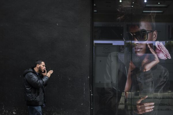 Homem fala de celular perto de cartaz em uma das ruas de Nova York - Sputnik Brasil