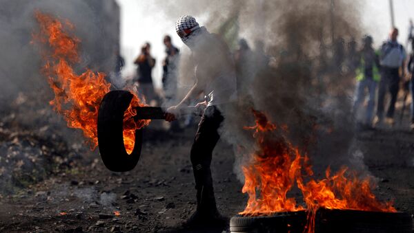 Palestino mascarado segurando um pneu em chamas durante confrontos com tropas israelenses em uma aldeia na Cisjordânia, 10 de novembro de 2017 - Sputnik Brasil