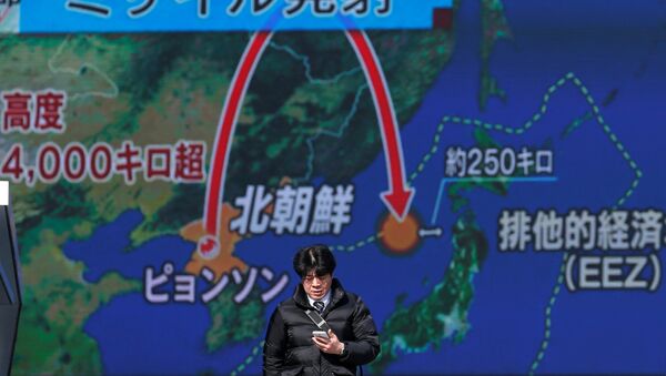 Um jovem passa na frente de uma televisão de rua em Tóquio, Japão, em 29 de novembro de 2017, durante uma transmissão da notícia sobre o lançamento de míssil pela Coreia do Norte - Sputnik Brasil